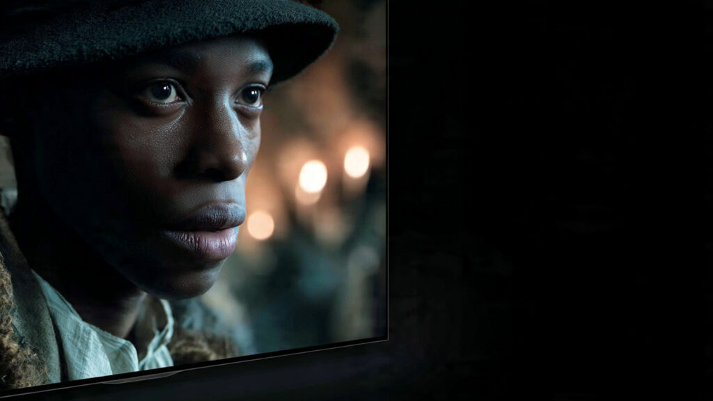 A close-up of a high-end OLED TV displaying a film with letterboxing, emphasizing the deep blacks and sharp image quality