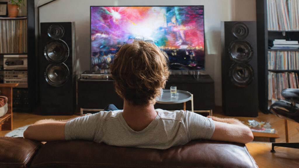 A person enjoying music in a living room with a sleek sound system