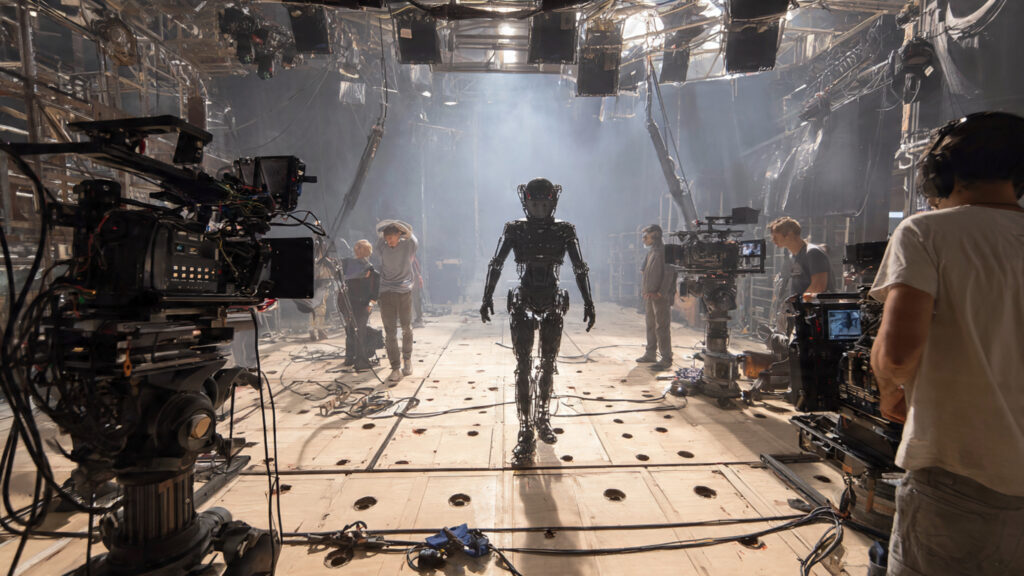 A behind-the-scenes shot of a film set showing motion capture technology and advanced camera rigs being used for an action sequence.