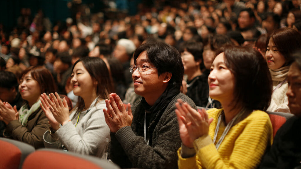 Audience members engaged during a film screening at the Jeonju International Film Festival, highlighting the communal experience of cinema