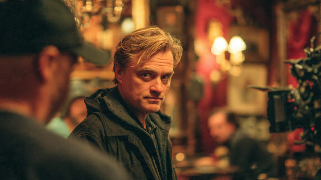 Christopher Nolan directing a scene on set with a serious expression