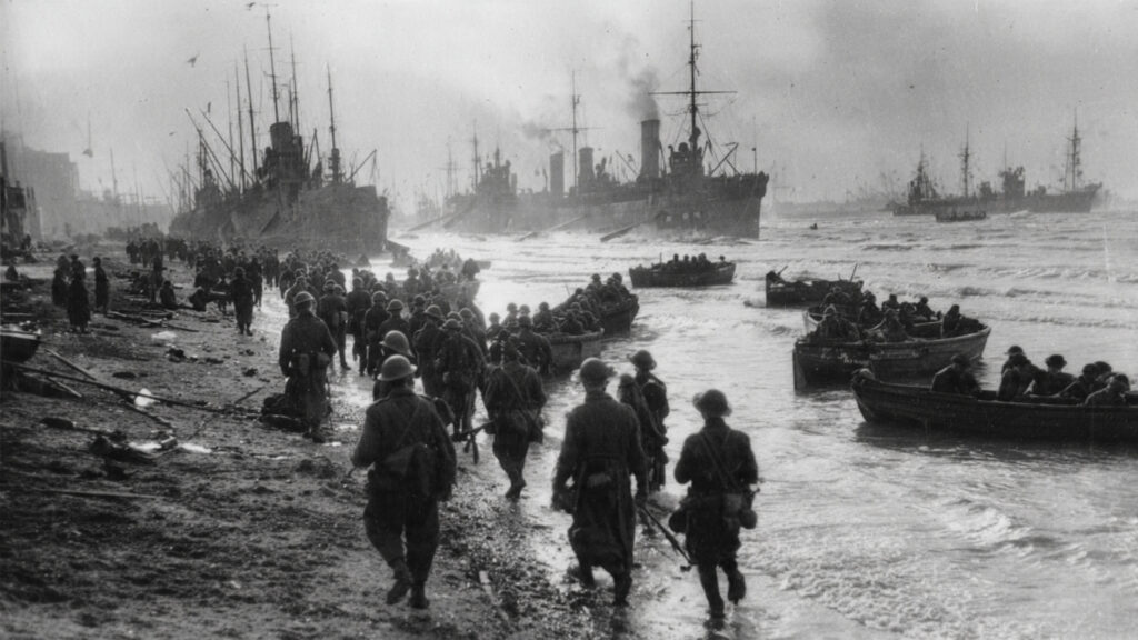  Soldiers being evacuated from the beach of Dunkirk onto small boats, with larger ships in the distance
